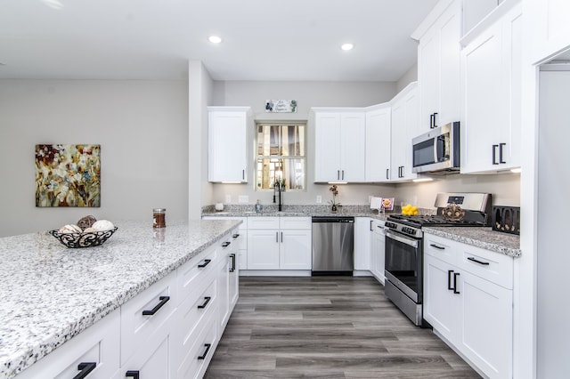 kitchen featuring dark wood-type flooring, sink, white cabinets, stainless steel appliances, and light stone countertops