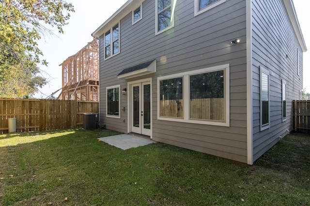 back of property with central AC unit and a yard