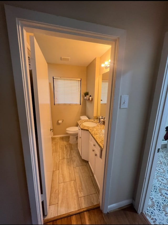 bathroom featuring wood-type flooring, vanity, and toilet