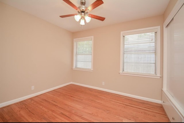 spare room featuring ceiling fan, light wood-type flooring, and a healthy amount of sunlight