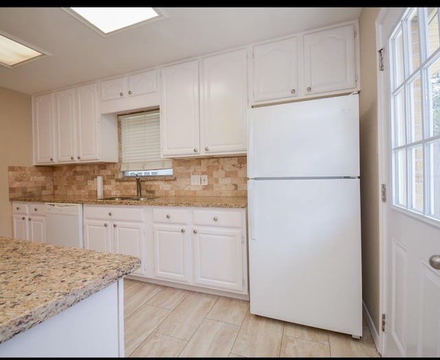 kitchen with white cabinetry, backsplash, white appliances, light stone countertops, and sink