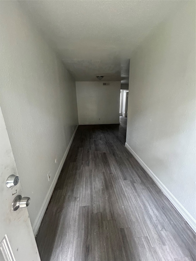 hall with a textured ceiling and dark wood-type flooring