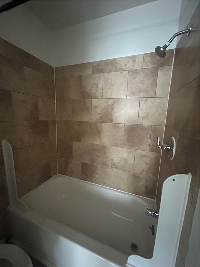 bathroom featuring toilet and tiled shower / bath