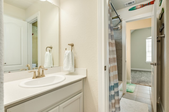 bathroom featuring tile patterned flooring, walk in shower, and vanity