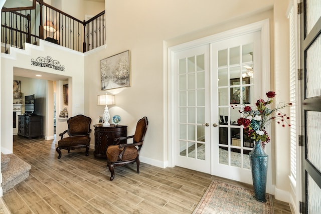 living area with a high ceiling, hardwood / wood-style floors, and french doors