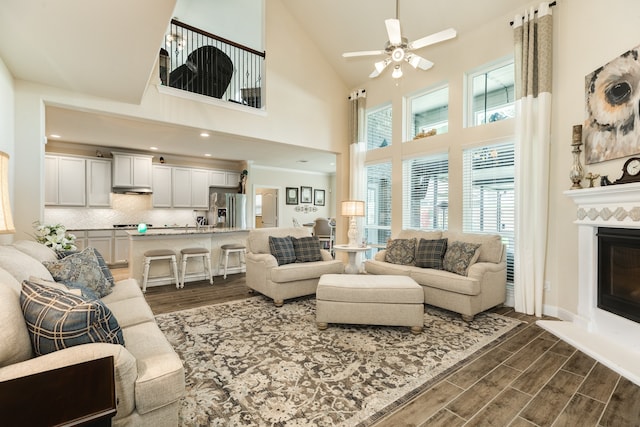 living room featuring dark wood-type flooring, high vaulted ceiling, and ceiling fan