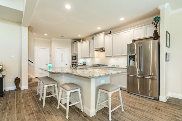 kitchen with an island with sink, wood-type flooring, a breakfast bar, white cabinets, and appliances with stainless steel finishes