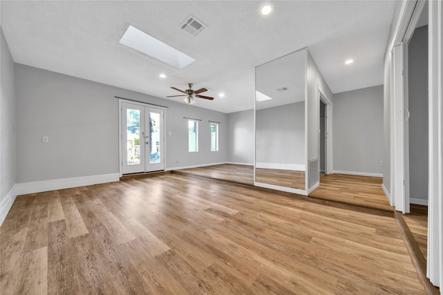 spare room featuring light wood-type flooring, ceiling fan, and a skylight