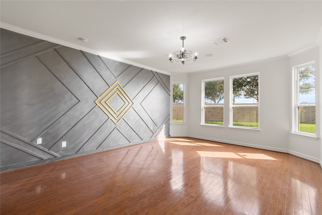 spare room with an inviting chandelier, crown molding, and a wealth of natural light