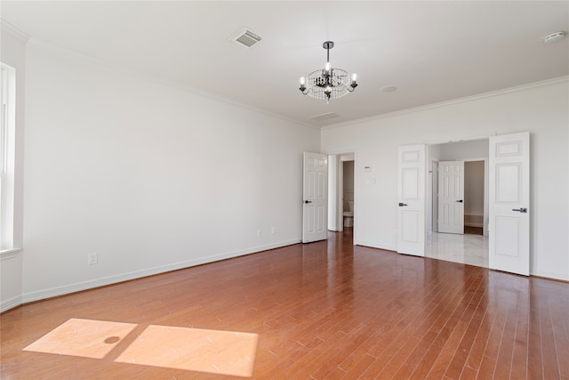 spare room with ornamental molding, hardwood / wood-style floors, and a chandelier