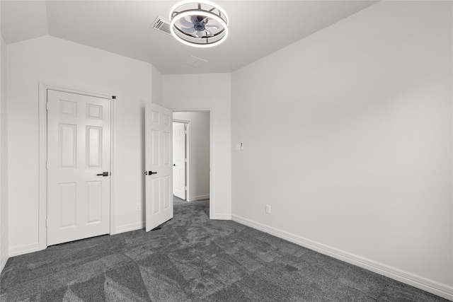 unfurnished bedroom featuring dark colored carpet and vaulted ceiling