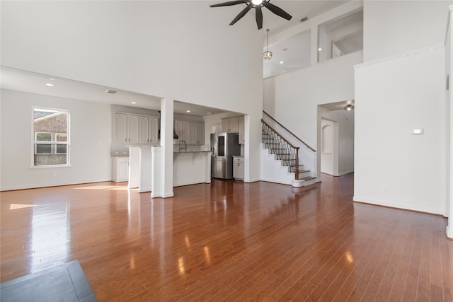 unfurnished living room with beamed ceiling, dark hardwood / wood-style flooring, ceiling fan, and high vaulted ceiling