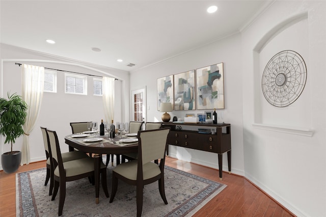 dining area featuring wood-type flooring and crown molding