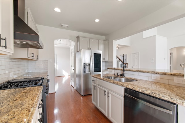 kitchen featuring white cabinetry, dark wood-type flooring, appliances with stainless steel finishes, and wall chimney range hood