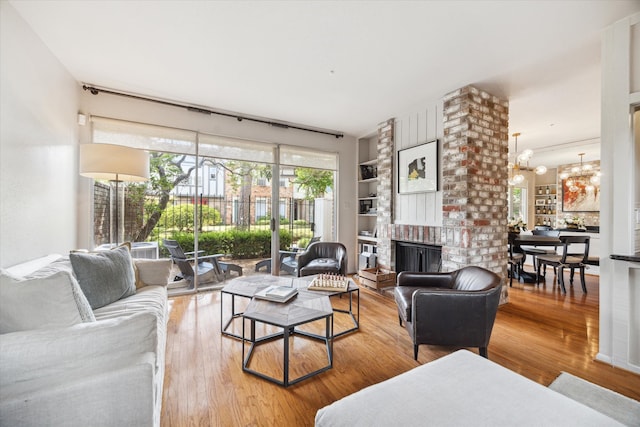 living room featuring an inviting chandelier, hardwood / wood-style floors, a fireplace, and built in features