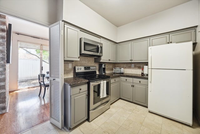 kitchen featuring gray cabinets, appliances with stainless steel finishes, light hardwood / wood-style floors, and tasteful backsplash