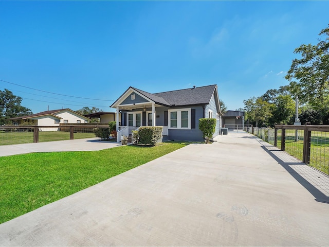bungalow with a front lawn, covered porch, driveway, roof with shingles, and fence