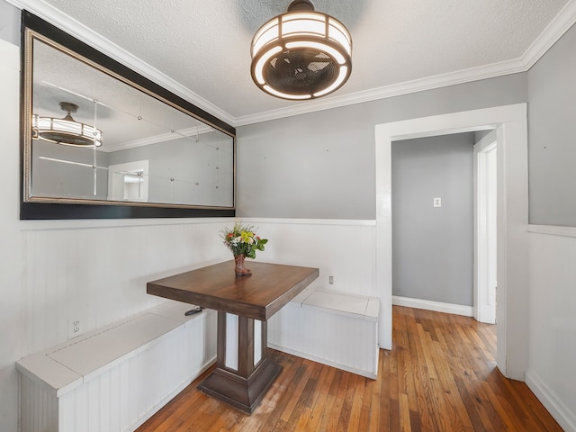 dining space with ornamental molding, a textured ceiling, and hardwood / wood-style flooring