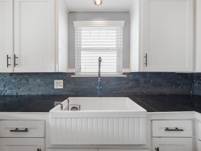 kitchen with a sink, white cabinetry, and tasteful backsplash