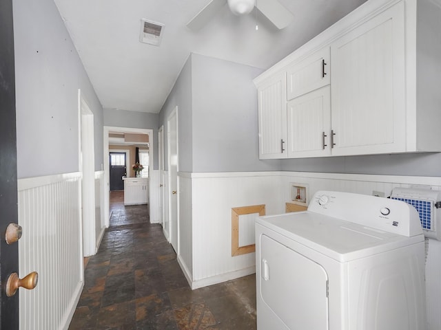 laundry room with stone tile flooring, cabinet space, wainscoting, and washer / dryer