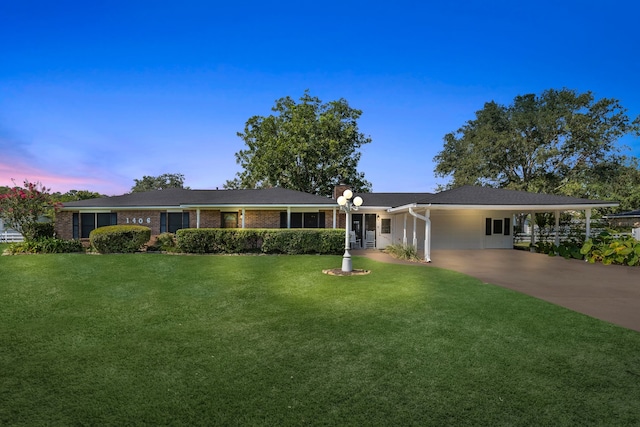 ranch-style home featuring a carport, brick siding, concrete driveway, and a front yard