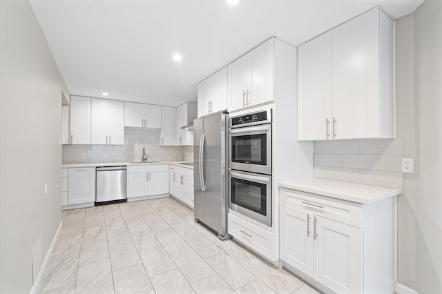 kitchen featuring white cabinets, backsplash, appliances with stainless steel finishes, and sink