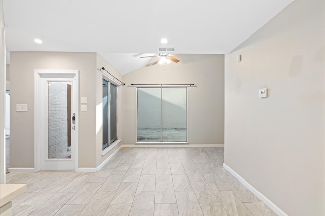 spare room with a barn door, vaulted ceiling, and ceiling fan