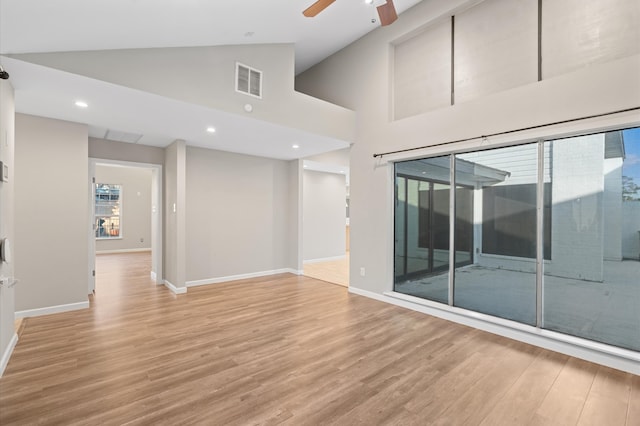 empty room with light hardwood / wood-style flooring, ceiling fan, and high vaulted ceiling