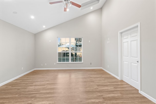 empty room with ceiling fan, light hardwood / wood-style flooring, and high vaulted ceiling