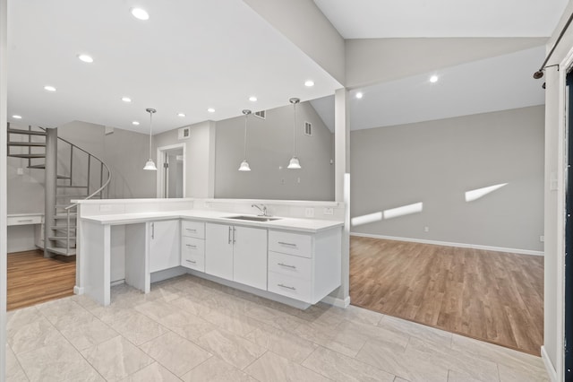 kitchen with white cabinetry, pendant lighting, lofted ceiling, light hardwood / wood-style flooring, and sink