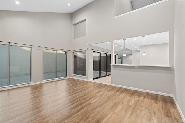 unfurnished room featuring light hardwood / wood-style floors and a towering ceiling