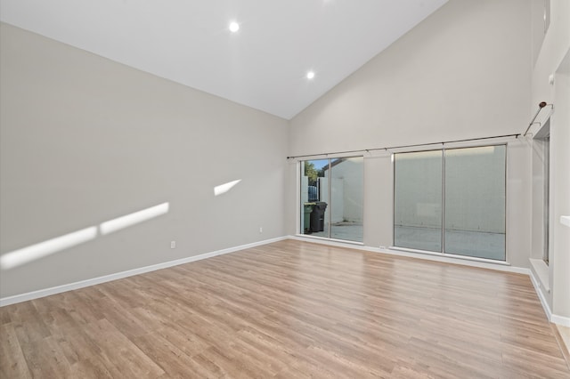 spare room with high vaulted ceiling and light hardwood / wood-style floors