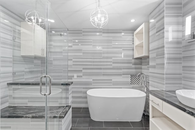 bathroom featuring an inviting chandelier, shower with separate bathtub, vanity, and tile walls