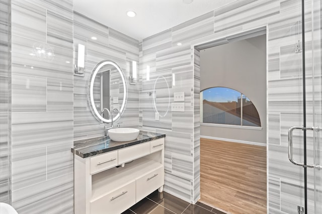 bathroom featuring tile walls, vanity, hardwood / wood-style floors, and a shower with shower door