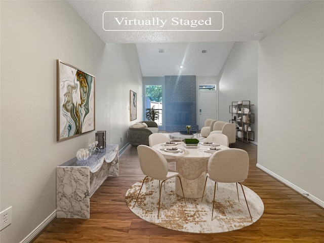 dining room with dark hardwood / wood-style flooring, a textured ceiling, and vaulted ceiling