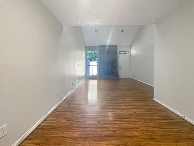 interior space with a textured ceiling, dark wood-type flooring, and lofted ceiling