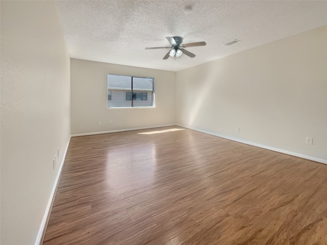 empty room with a textured ceiling, dark hardwood / wood-style floors, and ceiling fan