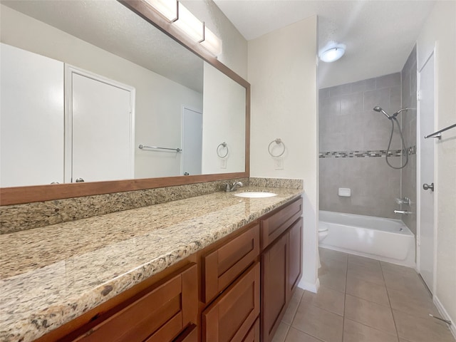 full bathroom with tile patterned flooring, vanity, tiled shower / bath combo, and toilet