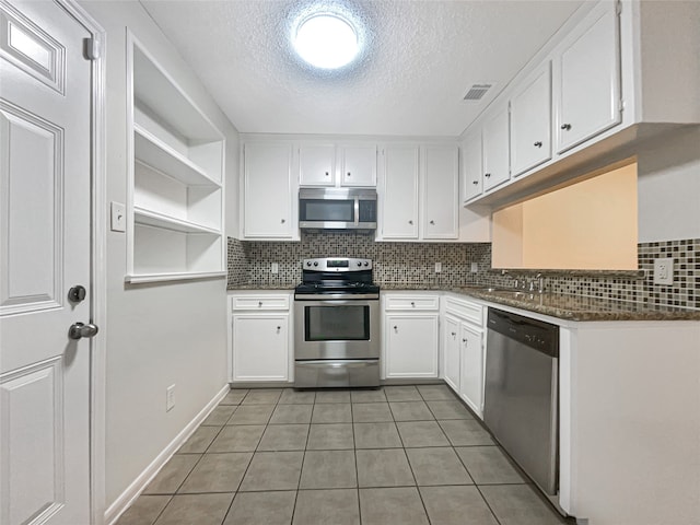 kitchen with decorative backsplash, a textured ceiling, light tile patterned flooring, white cabinetry, and stainless steel appliances