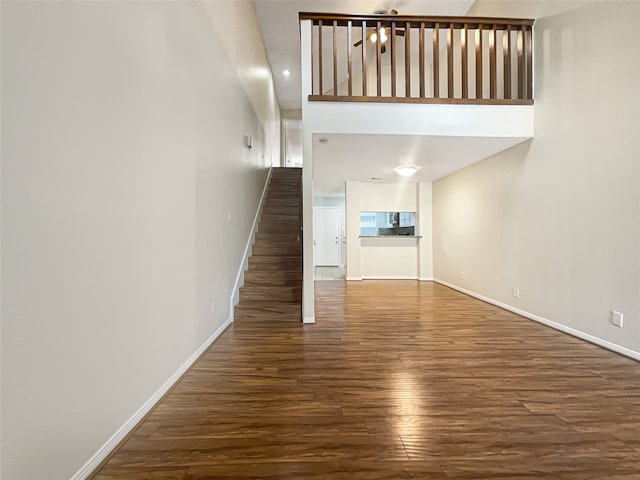 unfurnished living room featuring a high ceiling and dark hardwood / wood-style floors