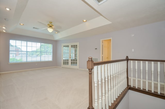 carpeted empty room featuring french doors, ceiling fan, and a tray ceiling