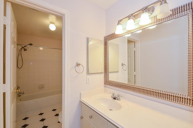 full bathroom featuring tiled shower / bath, vanity, a textured ceiling, and toilet