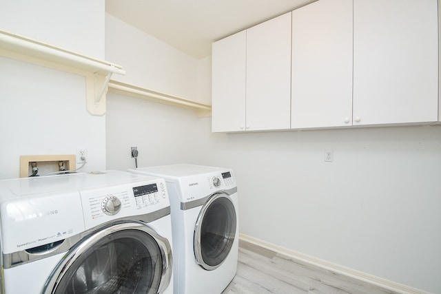 laundry room with cabinets, washing machine and dryer, and light wood-type flooring