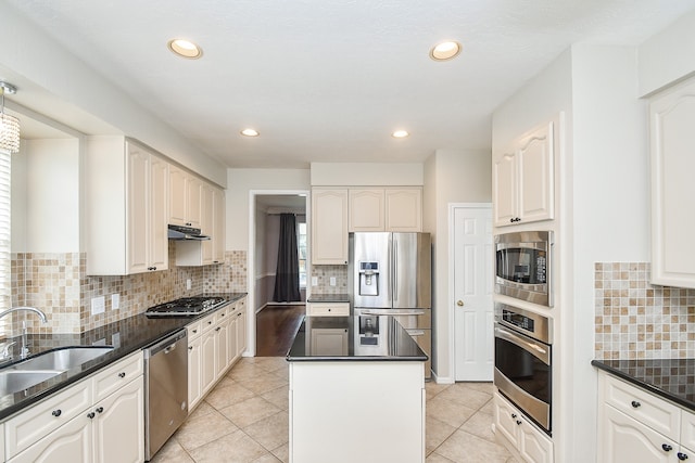 kitchen with white cabinets, light tile patterned floors, appliances with stainless steel finishes, a kitchen island, and sink