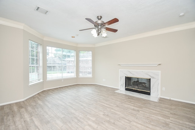 unfurnished living room with ceiling fan, a premium fireplace, light hardwood / wood-style flooring, and ornamental molding