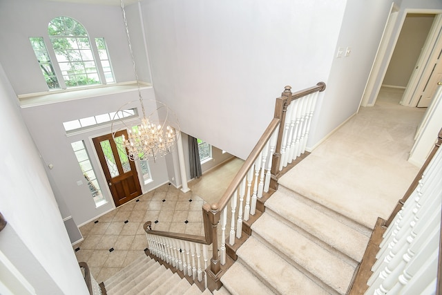 carpeted entrance foyer with a high ceiling and an inviting chandelier