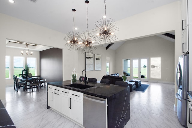 kitchen with appliances with stainless steel finishes, white cabinetry, a chandelier, sink, and a center island