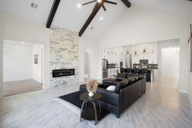 living room with ceiling fan, high vaulted ceiling, beamed ceiling, and a fireplace