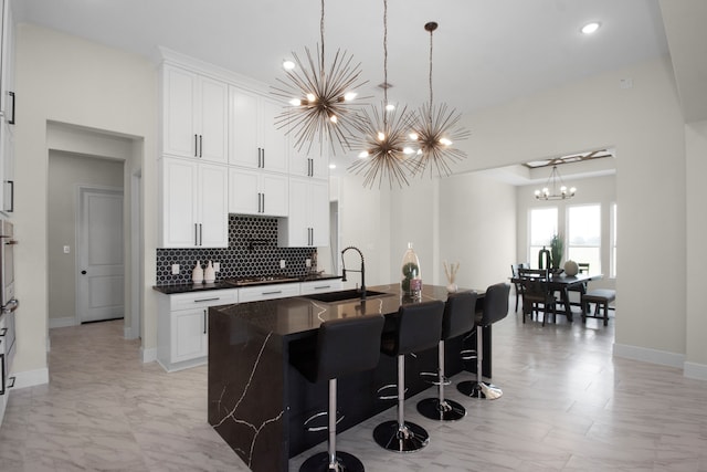 kitchen featuring white cabinetry, sink, a center island with sink, and hanging light fixtures