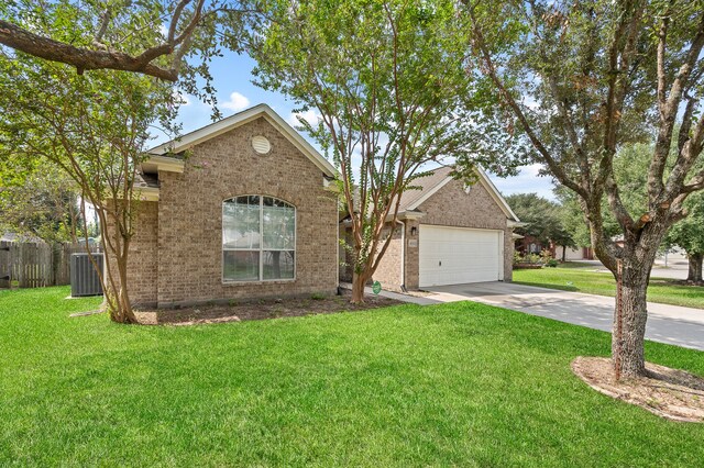 view of front facade with a front yard, a garage, and central AC unit